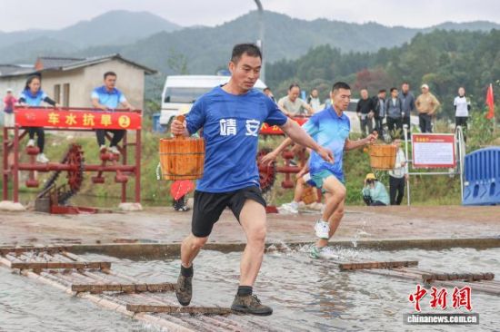 图为11月5日,江西宜春,车水抗旱项目中,选手提桶通过放置在水面上的竹排。刘力鑫 摄 图为11月5日,江西宜春,车水抗旱项目中,选手提桶通过放置在水面上的竹排。刘力鑫 摄