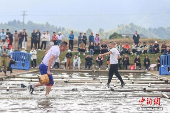 图为车水抗旱项目中,选手提桶通过放置在水面上的竹排。中新社记者 刘力鑫 摄 图为车水抗旱项目中,选手提桶通过放置在水面上的竹排。中新社记者 刘力鑫 摄