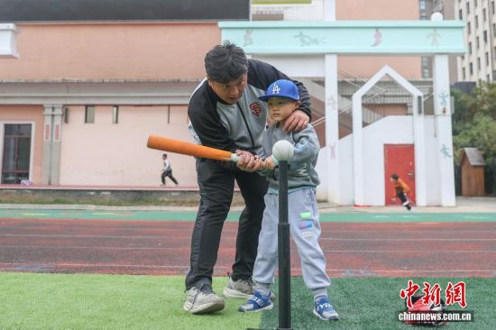 图为11月11日,江西南昌红谷滩区,吴军平在南昌大学附属小学(前湖分校)的棒垒球课上,手把手教小学生如何挥棒。吴军平很享受陪伴孩子们在运动中获得快乐并成长的过程。 图为11月11日,江西南昌红谷滩区,吴军平在南昌大学附属小学(前湖分校)的棒垒球课上,手把手教小学生如何挥棒。吴军平很享受陪伴孩子们在运动中获得快乐并成长的过程。