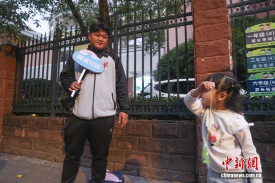 图为11月11日,江西南昌红谷滩区,吴军平在南昌大学附属小学(前湖分校)的棒垒球课结束后,拿着“棒球社团”的牌子,在学校门口等待家长来接学生回家。 图为11月11日,江西南昌红谷滩区,吴军平在南昌大学附属小学(前湖分校)的棒垒球课结束后,拿着“棒球社团”的牌子,在学校门口等待家长来接学生回家。