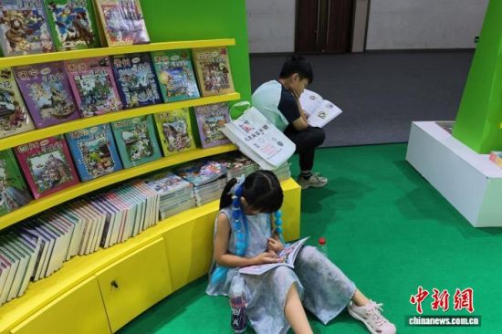 7月25日,孩子在书博会现场读书。曹丹 摄 7月25日,孩子在书博会现场读书。曹丹 摄