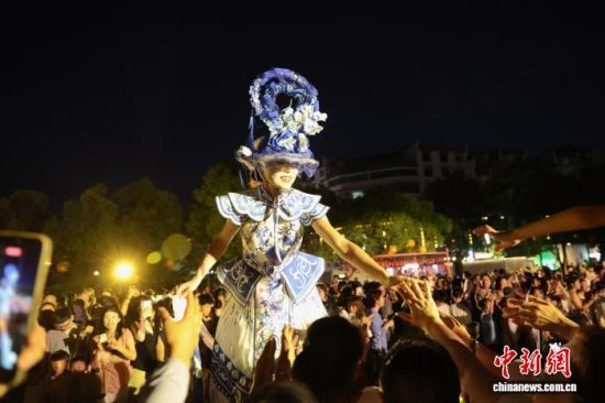7月30日晚,游客在江西景德镇陶阳里历史文化旅游区内与穿着青花瓷服饰的高跷演员互动。中新社记者 刘占昆 摄 7月30日晚,游客在江西景德镇陶阳里历史文化旅游区内与穿着青花瓷服饰的高跷演员互动。中新社记者 刘占昆 摄