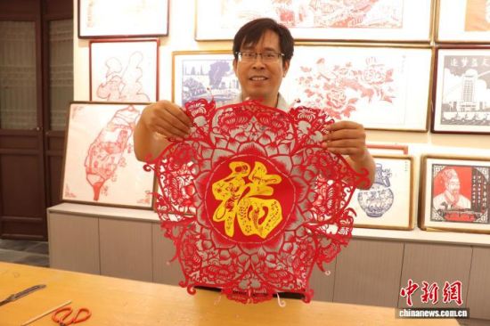 图为彭许平正在展示剪纸作品。 熊锦阳 摄 图为彭许平正在展示剪纸作品。 熊锦阳 摄