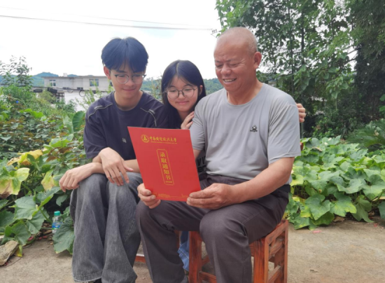 图为江西省宜春市上高县田心镇枧头村,黄秋生带着儿子、女儿坐在自家门口,一起端详刚收到的大学录取通知书。黄秋生用了不到八年时间实现人生转折,烟叶稳收、子女成才,日子正像田间的秧苗般节节攀升。王道玖摄 图为江西省宜春市上高县田心镇枧头村,黄秋生带着儿子、女儿坐在自家门口,一起端详刚收到的大学录取通知书。黄秋生用了不到八年时间实现人生转折,烟叶稳收、子女成才,日子正像田间的秧苗般节节攀升。王道玖摄