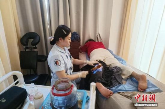 图为在江西省瑞金市中医院,医务人员运用火熨术中医疗法为患者开展理疗服务。吴思雨 摄 图为在江西省瑞金市中医院,医务人员运用火熨术中医疗法为患者开展理疗服务。吴思雨 摄